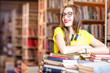 © rh2010 - Portrait of young enthusiastic female student studying with a lot of books at the library