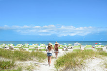 Girls Walking On The Beach On Summer Vacation.  Beach Chairs And Parasols On Beautiful White Sand In The Background.  Gulf Of Mexico, Clearwater Beach, Florida, USA.