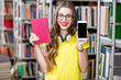 © rh2010 - Young smiling student holding book and smart phone with empty screen standing at the library. Mobile application concept