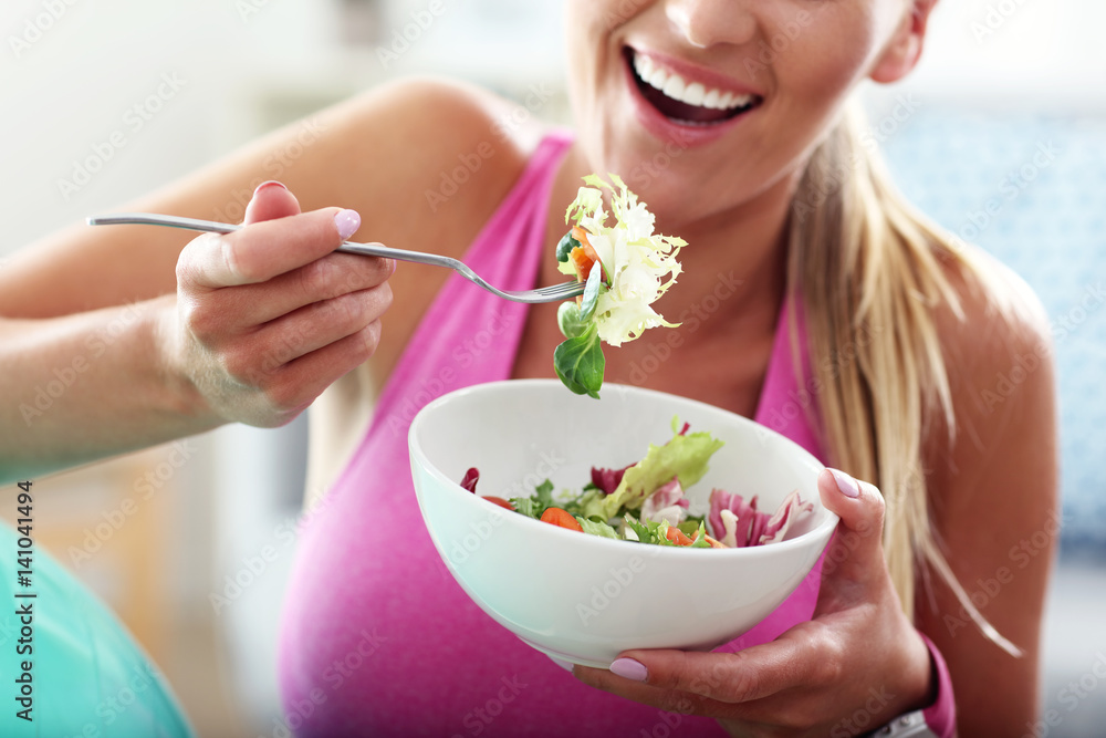 Young woman eating healthy salad after workout - obrazy, fototapety, plakaty 