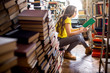 © rh2010 - Young woman student listening to the music sitting on the heap of books at the old library