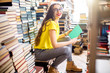 © rh2010 - Young woman student listening to the music sitting on the heap of books at the old library