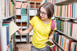 © rh2010 - Young happy and enthusiastic female student searching books on the shelves at the library