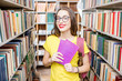 © rh2010 - Young happy and enthusiastic female student searching books on the shelves at the library