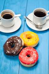 Two cups with coffee and donuts on a blue wooden table