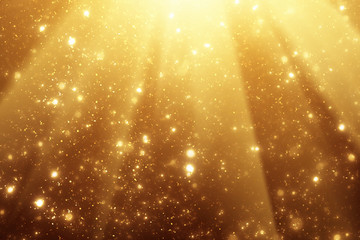 Golden rays and sparkles or glitter lights. Merry Christmas festive background.defocused circle bokeh or particles
