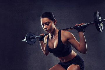 Wall Mural - young woman flexing muscles with barbell in gym