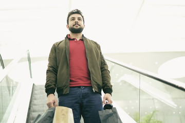 Bearded 30-35 years man shopping with bags in mall center outdoors with casual clothes.