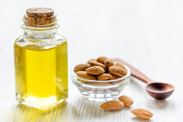 cosmetic and therapeutic almond oil on light wooden background