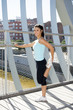 © Wordley Calvo Stock - young beautiful athletic sport woman stretching after running crossing modern metal city bridge