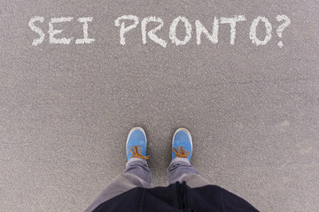 Wall Mural - Sei pronto?, Italian text for Are You Ready? text on asphalt ground, feet and shoes on floor