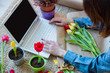 © Simonforstock - young woman looking how to wrap gift in the internet near flowers on the floor