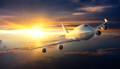 Wall Mural - airplane flying above clouds during sunset