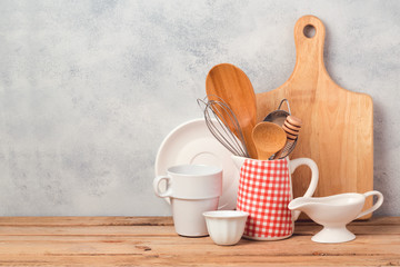 Wall Mural - Kitchen utensils and tableware on wooden table over rustic background with copy space