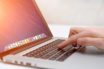 Hand typing on a keyboard of laptop with operating system screen on background