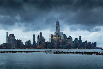 Fototapete - New York City Financial District skyline in early morning from across the Hudson River. Low storm clouds over the skyscrapers of Lower Manhattan