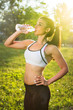 © Bojan - Young smiling woman drinking water from bottle after fitness sport exercise outdoors at sunset.