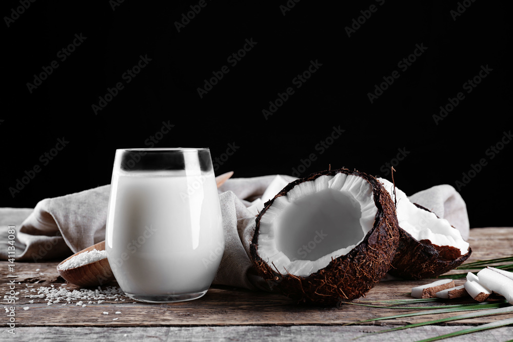 Composition with fresh coconut milk on wooden table against dark background