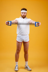 Wall Mural - Young athletic man exercising with chest expander or resistance band