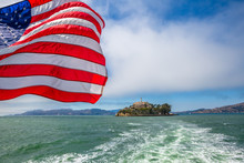 Alcatraz Island In San Francisco Bay Skyline, California, United States. Sea View From Boat To Alcatraz With American Flag Waving. Freedom And Travel Concept. Icon And Landmark Of San Francisco.