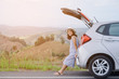 © tanasan - Woman traveler sitting on hatchback car with mountain background in vintage tone