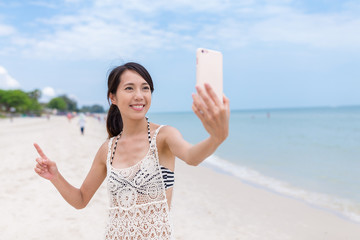 Sticker - Woman taking sefie with cellphone in sand beach