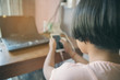 © prachid - Asian little cute girl play game from smartphone, happy kid using internet with mobile phone at coffee shop on wooden table, laptop for working at home.