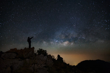 Wall Mural - a man is standing next to the milky way galaxy pointing on a bright star on doi luang chiang dao mou
