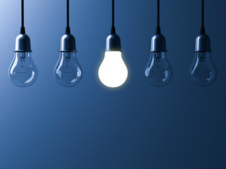 Fototapete - One hanging light bulb glowing different and standing out from unlit incandescent bulbs with reflection on dark blue background , leadership and different business creative idea concept. 3D rendering.