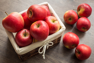 Juicy apples in the basket and scattered on the table.