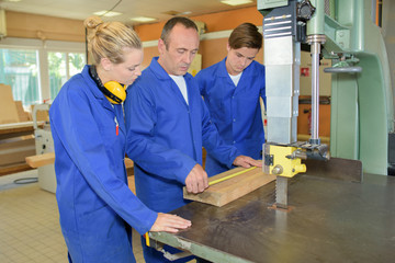 Wall Mural - Carpenter measuring wood, being watched by two apprentices