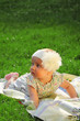© zwiebackesser - Surprised beautiful baby girl lying on the grass. Nature, holidays, childhood concept.