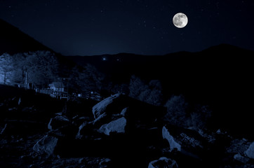 beautiful night view of bright magical moon with dark blue clouds under the hills