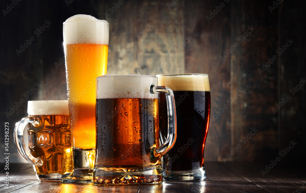 Four glassed of beer on wooden background - obrazy, fototapety, plakaty 