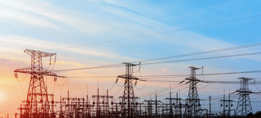 Silhouette of high voltage electrical pole. Sunset sky background.