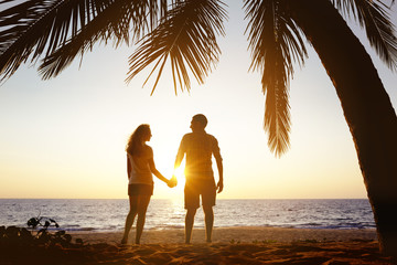 Happy couple sunset beach under palm