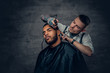 © Fxquadro - Male barber cutting the beard to Black stylish man.