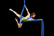 Beautiful young, athletic sexy woman professional aerial circus artist with redhead in yellow costume posing diagonal in the air, light in the darkness. Dancing in the air with balance.
