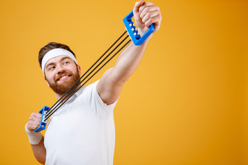 Wall Mural - Portrait of a cheerful sportsman doing fitness exercises with expander