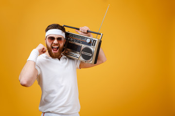 Wall Mural - Screaming young man wearing sunglasses holding tape recorder