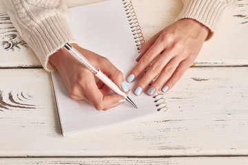 Fotomurales - Beautiful female hands write in notebook.