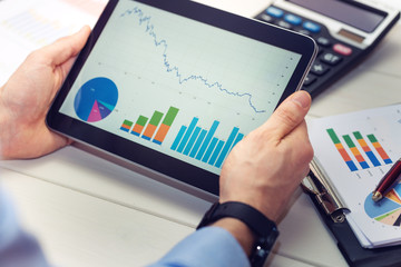 businessman holding digital tablet with graphs and charts report