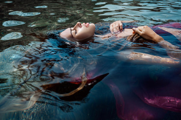 beautiful young woman in red dress laying dowm in water