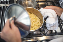 Chef Lifting Lid On Pan Of Spaghetti On Stove, Elevated View