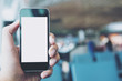 © Farknot Architect - Mockup image of hand holding black mobile phone with blank white screen in airport background