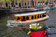 Famous Amsterdam with basket of colorful tulips against boat in Holland