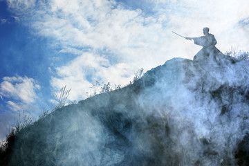Wall Mural - Silhouette of a warrior with a sword in the smoke of a mountain war