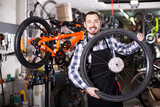 Fototapeta Na drzwi - man in apron considering composition of wheel for bicycle