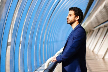 Wall Mural - An Arab man in a suit holds onto the railing in glass transition