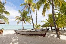 Old Wooden Fishing Boat On A Tropical Paradise Island With Coconut Palm Trees In The Background